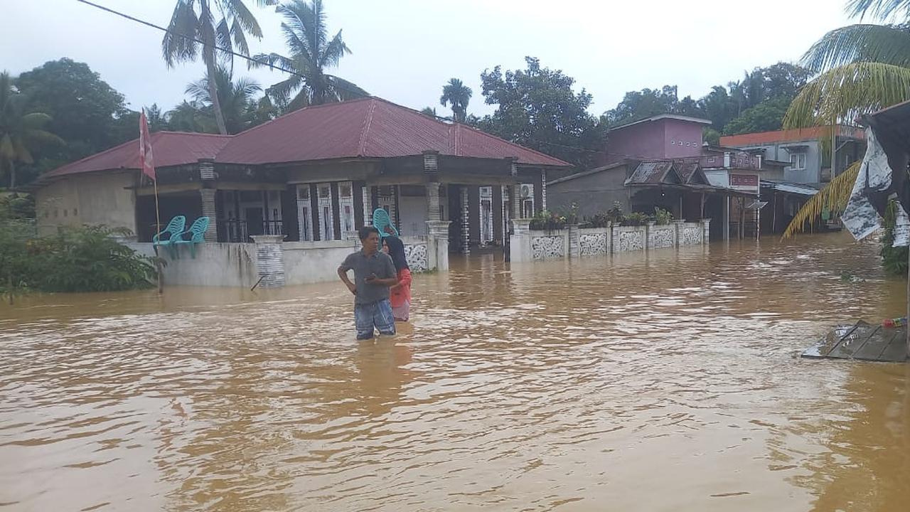 Warga mengarungi banjir karena tingginya intensitas hujan di Riau.