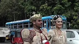 Sepasang pengantin Sri Lanka berjalan menyusuri jalan utama di pusat kota Kandy, 22 September 2017. Pasangan pengantin tersebut diperiksa oleh polisi karena melibatkan sekitar 250 siswa untuk memegang saree atau gaun pengantin pada jam sekolah. (STR/AFP)