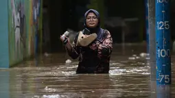 Warga melintasi banjir di kawasan Kebon Pala, Kampung Melayu, Jakarta Timur, Sabtu (16/7/2022). Meskipun ketinggian air sudah mencapai paha orang dewasa, warga setempat belum memutuskan untuk mengungsi. (merdeka.com/Imam Buhori)