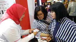 Karyawan Bank DKI menjelaskan aplikasi JakOne Mobile kepada pengunjung Pekan Raya Jakarta di Jakarta (23/5). Bank DKI turut berpartisipasi dalam PRJ sebagai alat pembayaran dengan menggunakan fitur scan to pay. (Liputan6.com/Pool/Budi)