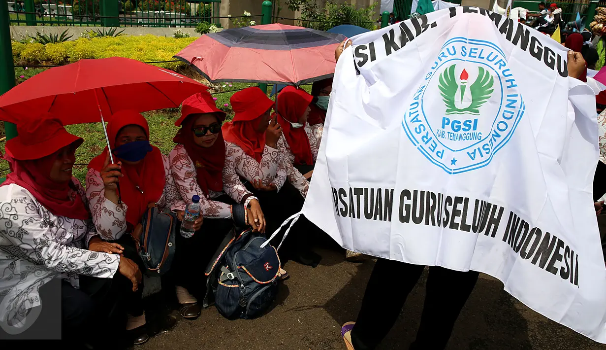 Sejumlah guru berteduh saat mengelar unjuk rasa di Gedung DPR/MPR, Jakarta, Kamis (12/1). Dalam aksinya mereka menuntut kenaikan upah dan mendesak pemerintah kususnya DPR agar tidak melakukan diskriminasi terhadap guru swasta. (Liputan6.com/Johan Tallo)