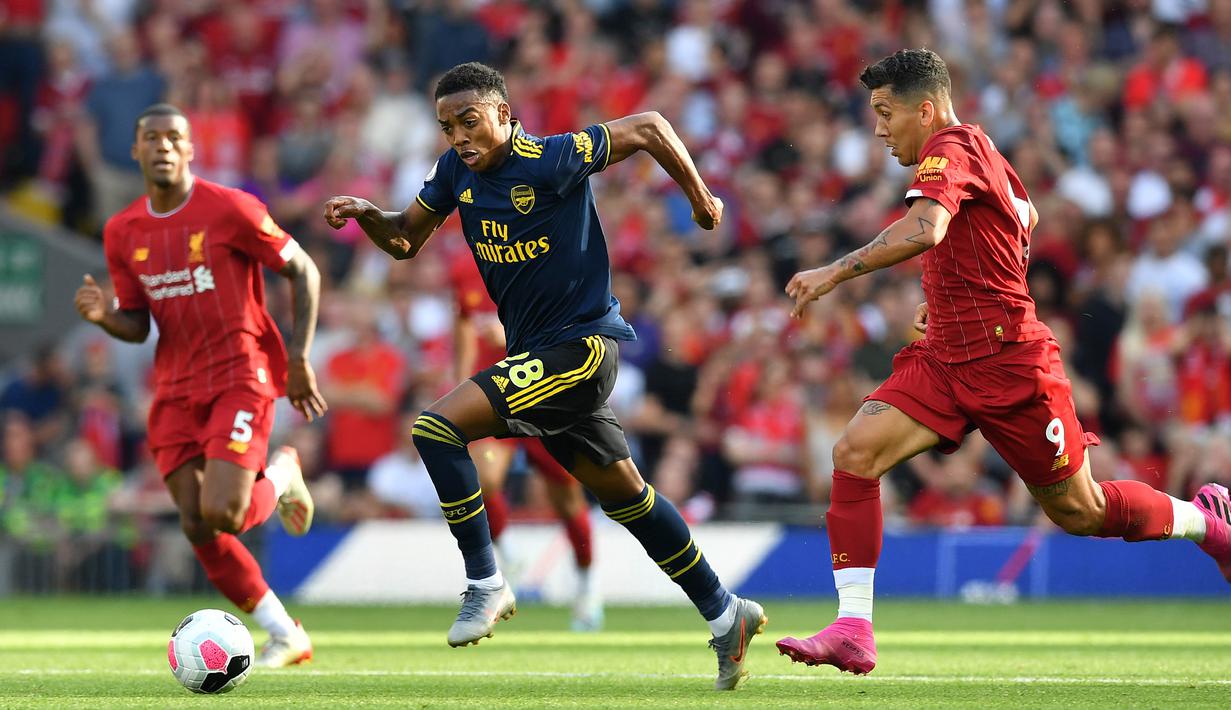 Gelandang Arsenal Joe Willock (tengah) menggiring bola melewati pemain Liverpool Roberto Firmino (kanan) saat bertanding dalam Liga Inggris di Stadion Anfield, Liverpool, Inggris, Sabtu (24/8/2019). Liverpool menang 3-1 dan kukuh di puncak klasemen sementara. (BEN STANSALL/AFP)