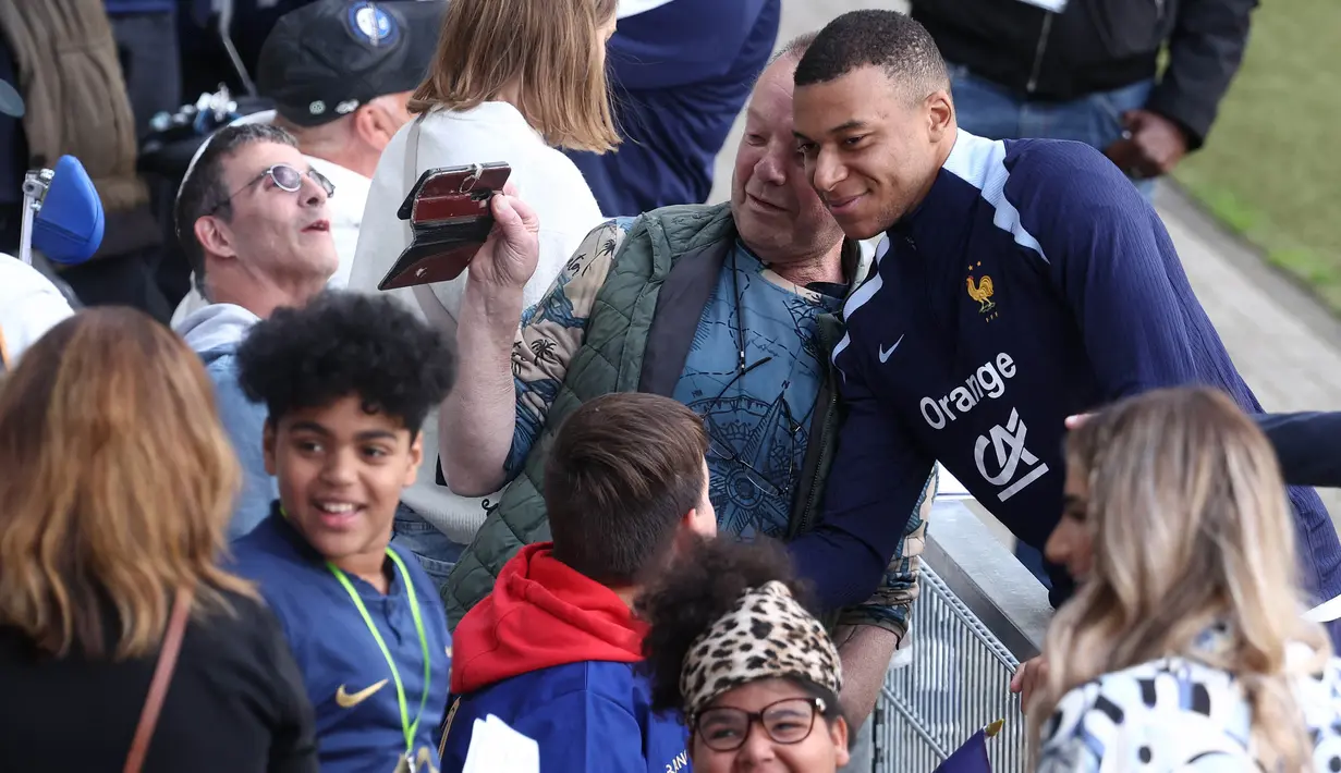 Kylian Mbappe menyempatkan menyapa dan melayani permintaan berswafoto bersama para suporter yang menyaksikan langsung sesi latihan resmi timnas Prancis. (FRANCK FIFE/AFP)