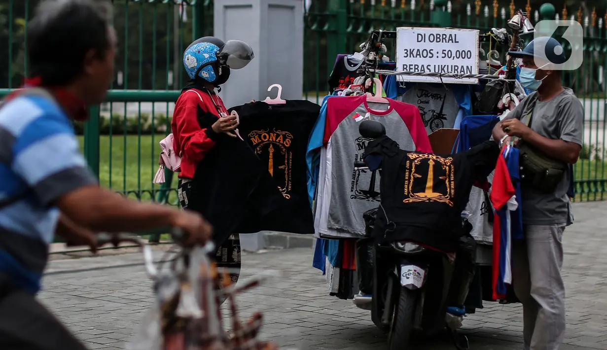 Pedagang kaos melayani pembeli saat PPKM level 3 di kawasan Monas, Jakarta, Sabtu (21/8/2021). Wagub DKI Jakarta Ahmad Riza Patria mengungkapkan, Jakarta sudah keluar dari zona merah setelah satu setengah bulan angka COVID-19 tinggi. (Liputan6.com/Johan Tallo)