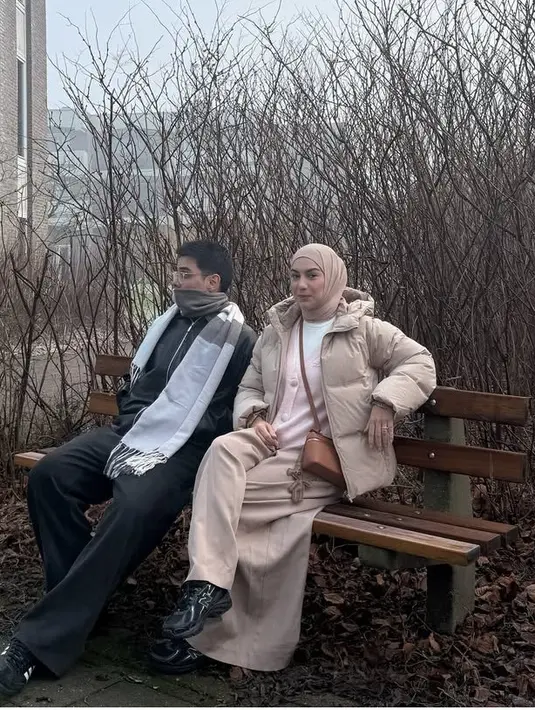 Irish Bella tampil serba coklat dari kerudung polos dengan model lilit leher serta padding jaket hingga celana loosenya. Dipadukan inner putih dan cardigan pink. Ia juga mengenakan sneaker hitam New Balance.  [@_irishbella_]