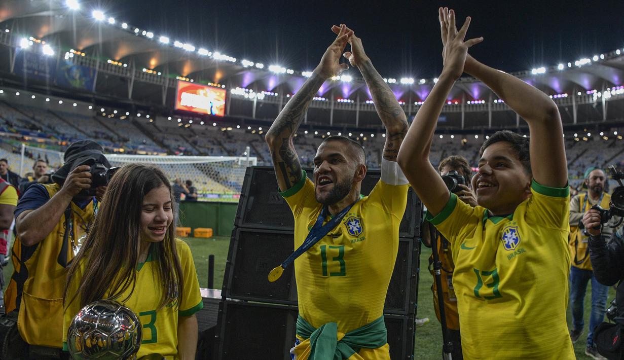 Bek Brasil, Dani Alves, bersama putranya merayakan gelar juara Copa America 2019 setelah mengalahkan Peru pada laga final di Stadion Maracana, Rio de Janeiro, Minggu (7/7). Brasil menang 3-1 atas Peru. (AFP/Carl De Souza)