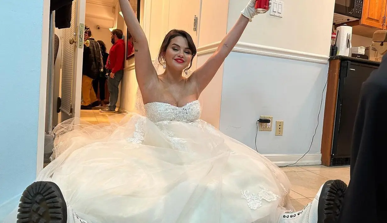 Potret unik Selena Gomez dengan gaun pengantin. Selena tampak duduk di lantai dengan pose tak biasa dan makeup bold bak pengantin sungguhan yang disempurnakan dengan lipstik merah. [Foto: Instagram/selenagomez]