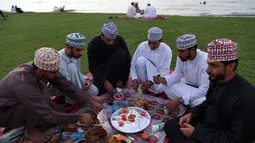 Warga Oman berkumpul untuk berbuka puasa di pantai di Muscat selama bulan suci Ramadhan pada 12 April 2022. Umat islam di seluruh dunia saat ini tengah melaksanakan bulan Ramadhan dan berpuasa selama satu bulan. (MOHAMMED MAHJOUB / AFP)