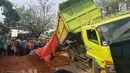 Warga berkerumun menyaksikan proses evakuasi bangkai mobil kecelakaan maut yang hancur tertindih badan truk muatan tanah di Karawaci, Tangerang, Kamis (1/8/2019). Sopir truk yang menimpa mobil dan menewaskan 4 orang itu kabur setelah kecelakaan maut terjadi. (Liputan6.com/Pramita Tristiawati)