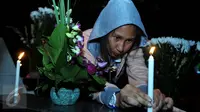 Warga keturunan Portugis menyalakan lilin saat ziarah ke makam yang terdapat di sebelah Gereja Tugu, Jakarta, Kamis (24/12). Tradisi nyekar itu dilakukan usai mengikuti ibadah kebaktian malam Natal di gereja. (Liputan6.com/Gempur M Surya)