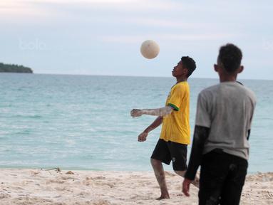 Seorang pemuda melakukan kontrol bola saat bermain bola dekat pantai di Desa Matwaer, Kei Kecil, Maluku (25/12/2017). Bermain bola di pasir menjadi daya tarik tersendiri bagi anak-anak dan pemuda desa. (Bola.com/Nick Hanoatubun)