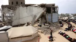 Meski harus berhadapan dengan ancaman bahaya dan reruntuhan bangunan, warga di Gaza tetap memadati lokasi salat Jumat pada 13 Maret 2026. Tampak dalam foto, umat Muslim Palestina berdoa saat salat Jumat terakhir di bulan suci Ramadan 1447 Hijriah, di luar Masjid Al-Talbani, yang dihancurkan oleh militer Israel di Khan Yunis, Jalur Gaza selatan pada Jumat 13 Maret 2026. (Bashar Taleb/AFP)