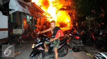 Seorang warga menyelamatkan diri dari kebakaran yang terjadi di belakang Senayan City, Jakarta, Minggu (3/7) dini hari. Sejumlah rumah semi permanen terbakar 38 mobil pemadam kebakaran dikerahkan. (Liputan6.com/Helmi Afandi)