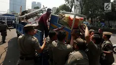 Petugas Satpol PP mengangkut gerobak milik pedagang buah keliling saat merazia pedagang kaki lima di kawasan Karet, Jakarta, Senin (17/7). Razia itu untuk membuat jera pedagang yang nakal dan tetap nekat berjualan di bahu jalan. (Liputan6.com/Johan Tallo)
