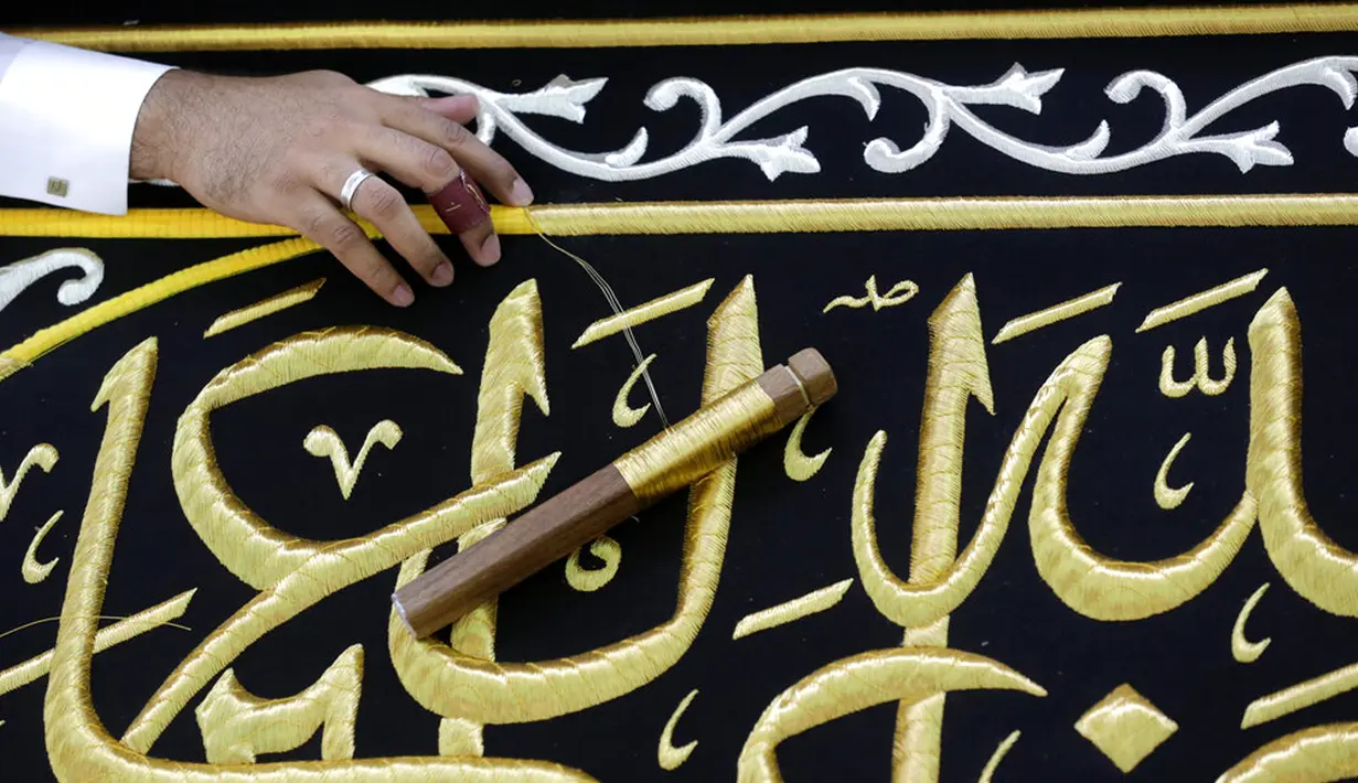 Pekerja menyulam kaligrafi Islam menggunakan benang berlapis emas pada tahap akhir pembuatan Kiswah Kabah di pabrik Kiswah di Mekah, Arab Saudi, Rabu (14/7/2021). Kiswah yang menutupi Kabah diganti setiap tahun untuk umrah atau haji. (AP Photo/Amr Nabil)