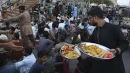 Relawan mendistribusikan makanan untuk warga saat berbuka puasa bersama selama bulan suci Ramadan di Karachi, Pakistan, Selasa (12/5/2020). Warga berbuka puasa bersama setelah pemerintah melonggarkan lockdown terkait pandemi virus corona COVID-19. (AP Photo/Fareed Khan)