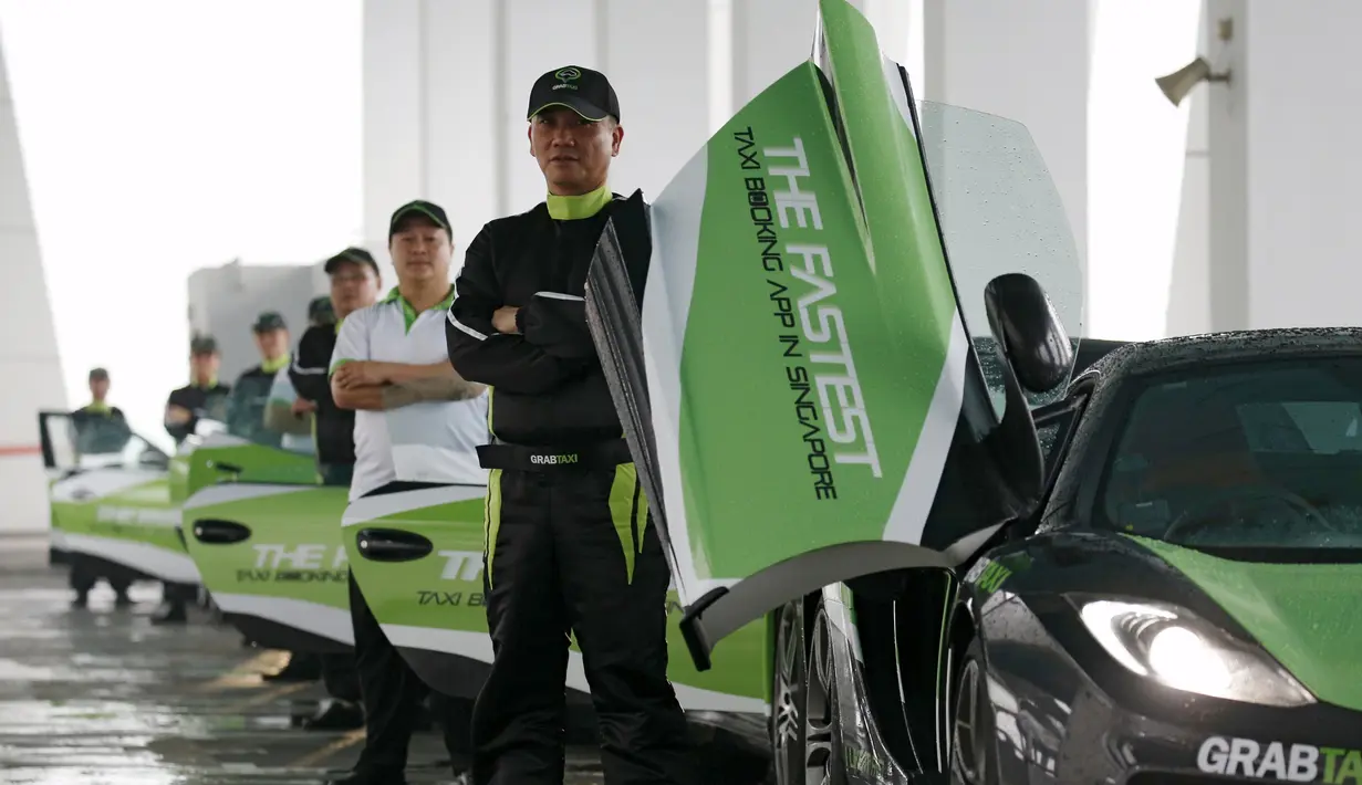 Pengemudi GrabTaxi berpose saat melakukan pemotretan dengan tujuh mobil mewah untuk pemotretan sebelum beroperasi di Singapura, Selasa (15/9). Mobil-mobil mewah itu akan melayani penumpang secara gratis selama musim balapan F1. (REUTERS/Edgar Su)