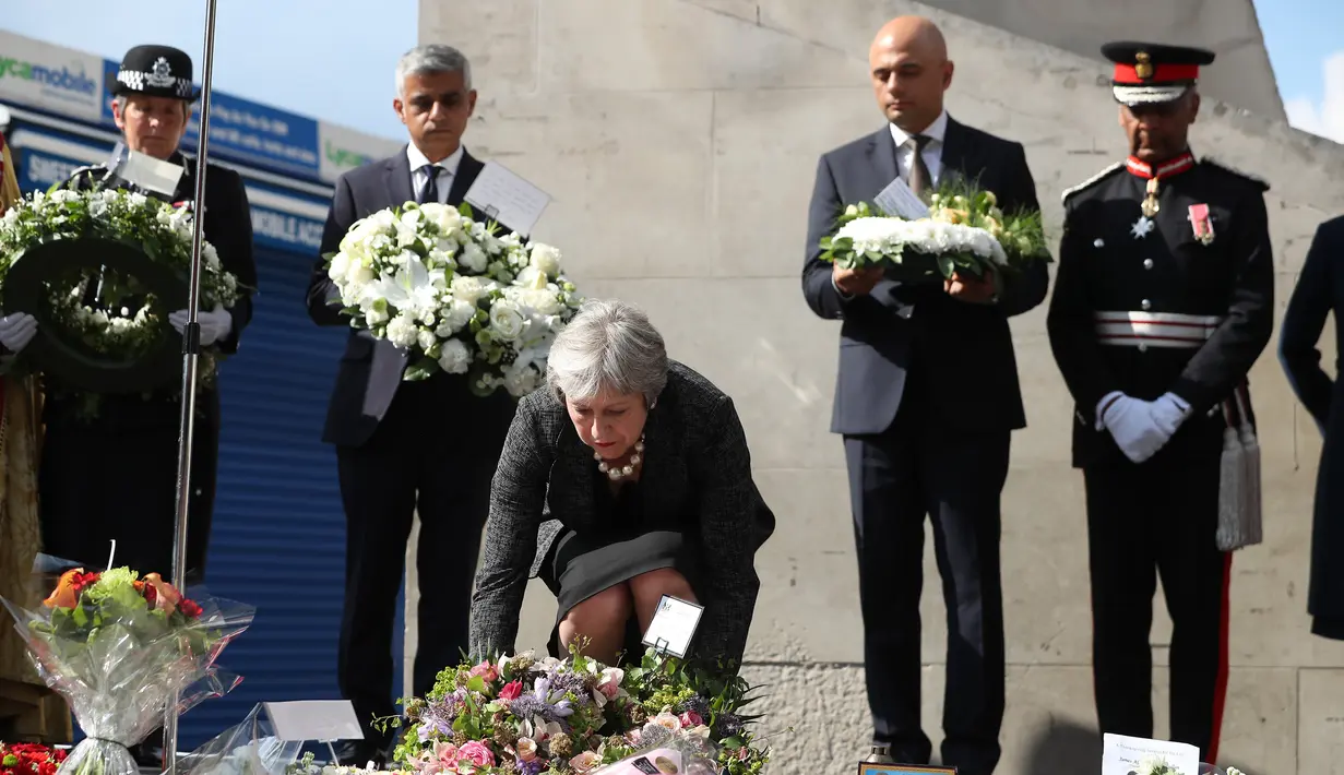 Perdana Menteri Inggris Theresa May menaruh bunga saat upacara peringatan setahun serangan teror Jembatan London, di London Bridge, Inggris (3/6). (AFP/Daniel Leal-Olivas)