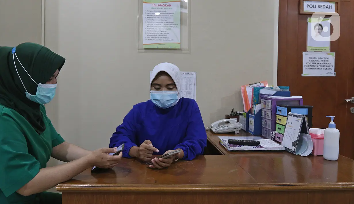 Tenaga kesehatan mengecek pesan singkat penerima vaksin COVID-19 di RSIA Tambak, Jakarta, Selasa (5/01/2021). Kementerian Kesehatan mengirimkan Short Message Service (SMS) blast secara serentak kepada penerima vaksin COVID-19 tahap pertama pada Kamis (31/12) lalu. (Liputan6.com/Herman Zakharia)