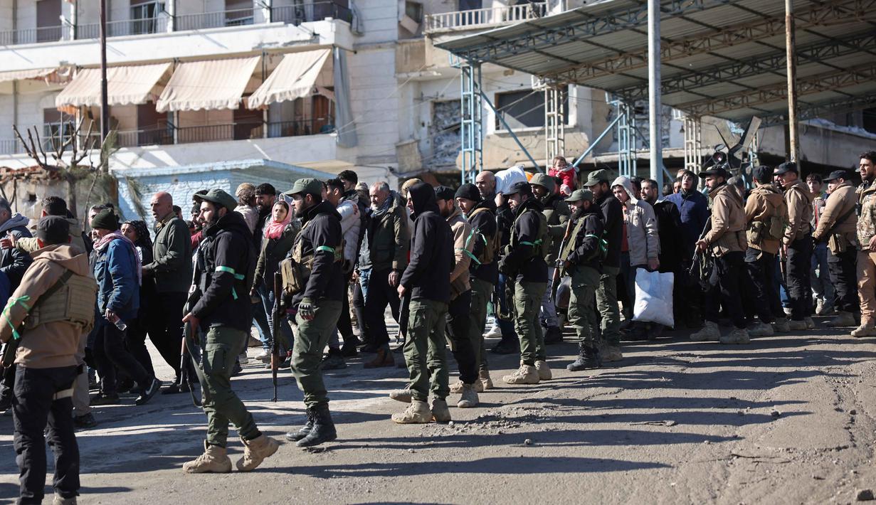 Untuk menjamin keselamatan warga sipil, otoritas Suriah membuka koridor kemanusiaan khusus bagi proses evakuasi. Tampak dalam foto, warga lingkungan Sheikh Maqsud dievakuasi dari zona berbahaya oleh anggota pasukan keamanan pemerintah Suriah, di Aleppo pada Sabtu 10 Januari 2026. (OMAR HAJ KADOUR/AFP)