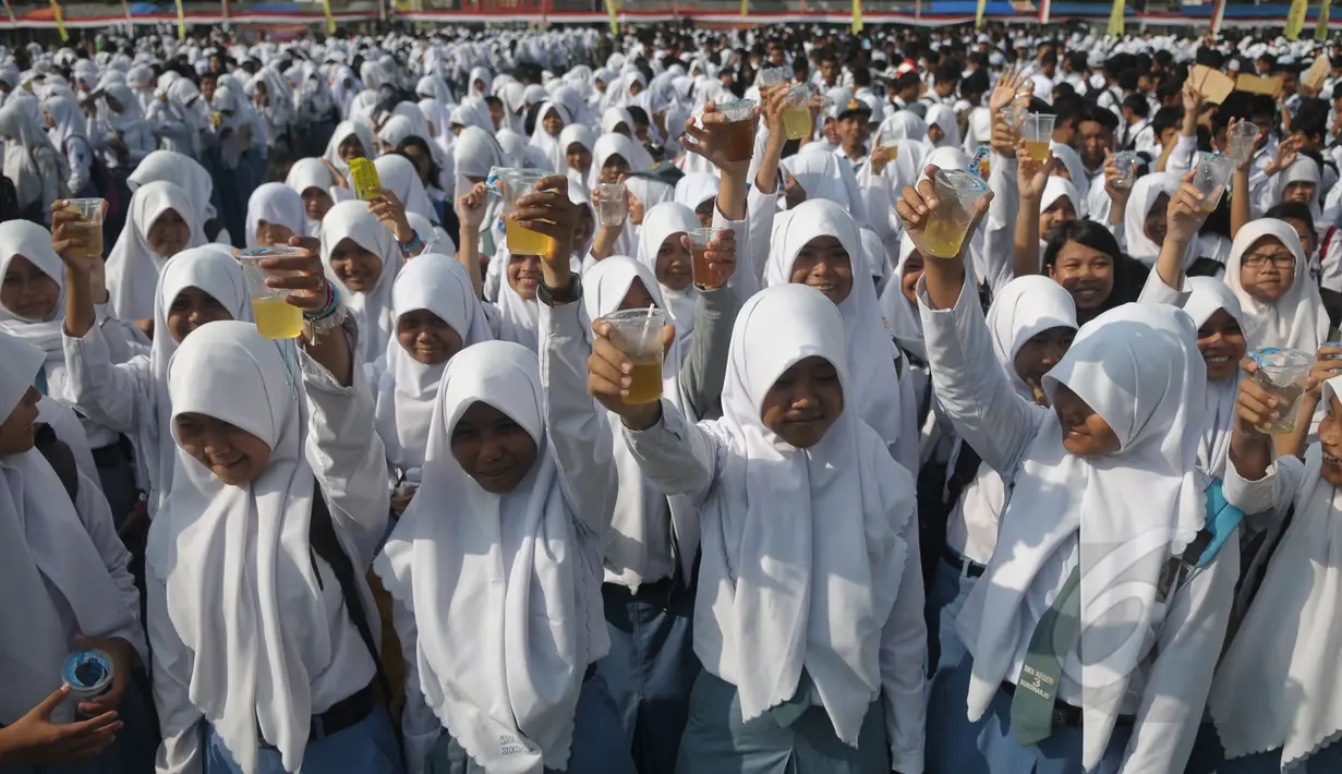 Ribuan pelajar mengangkat gelasnya saat minum jamu bersama di Alun-Alun Satya Negara Sukoharjo, Jawa Tengah, Rabu (1/4). Kegiatan tersebut dalam rangka pelestarian jamu ke masyarakat nasional maupun internasional. (Liputan6.com/Johan Tallo)