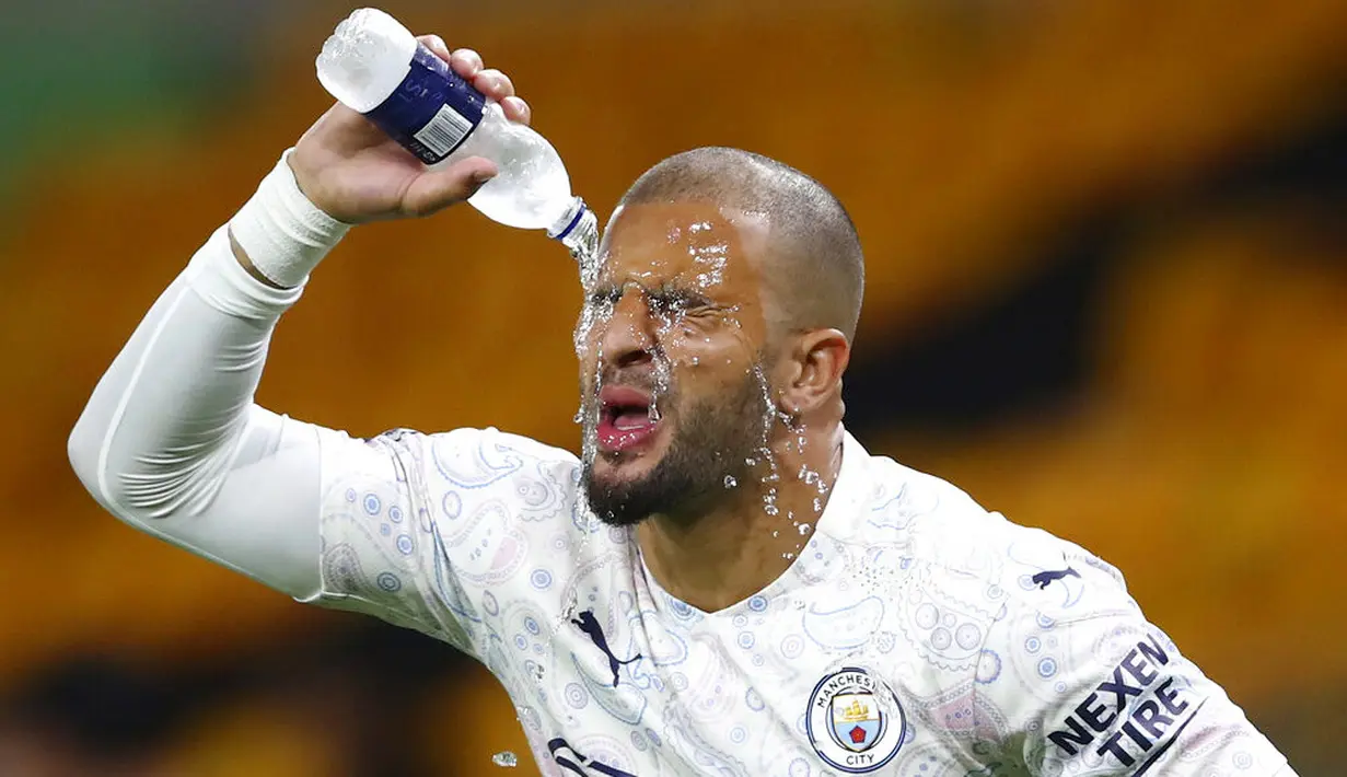 Bek Manchester City, Kyle Walker, membasahi wajahnya dengan air saat melawan Wolverhampton Wanderers pada laga Liga Inggris di Stadion Molineux, Senin (21/9/2020). Manchester City menang dengan skor 3-1. (Marc Atkins/Pool via AP)