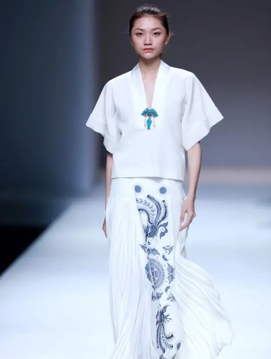 Seorang model berjalan diatas catwalk mengenakan rok putih bermotif seperti batik lasem cina rancangan desainer Xuefei Sun saat China Fashion Week di Beijing, Tiongkok (30/10). (AFP/STR)
