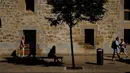 Seorang wanita berteduh di bawah pohon sambil menunggu bus saat musim panas, di Pamplona, Spanyol utara, (3/8). Dua orang tewas akibat sengatan panas di Spanyol ketika Eropa dilanda gelombang panas. (AP Photo/Alvaro Barrientos)