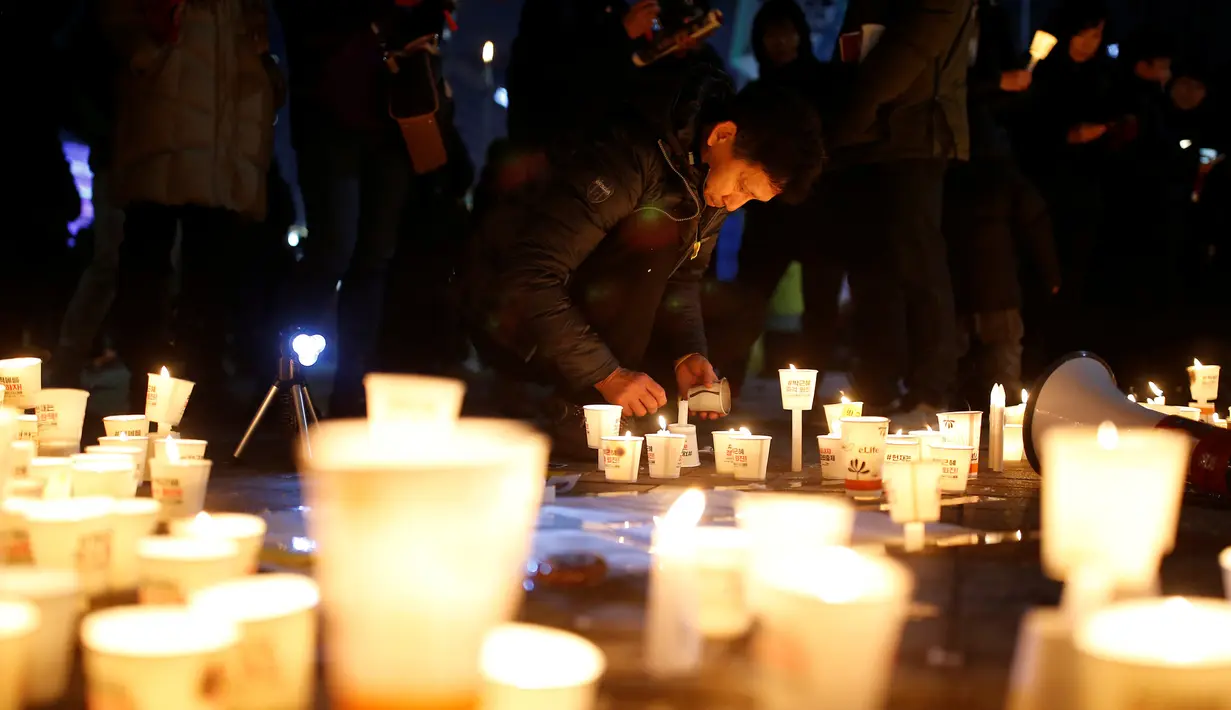 Seorang pria menyalakan lilin saat unjuk rasa menuntut penggulingan Presiden Park Geun-hye pada malam pergantian tahun di Seoul, Korsel, Sabtu (31/12). Sedangkan Korut mengawali Tahun Baru dengan pertunjukan kembang api di Pyongyang. (REUTERS/Kim Hong-Ji)