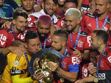 Kapten tim Flamengo Diego (kiri) mencium trofi disaksikan rekan satu timnya usai menjuarai Liga Brasil di Sao Paulo, Kamis (25/2/2021). (Foto: AFP/Nelson Almeida)