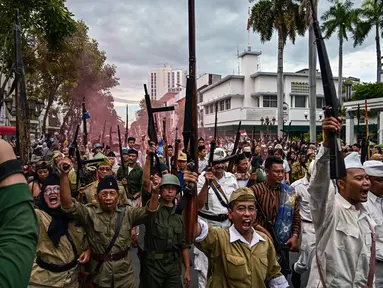 Anggota Komunitas Roode Brug Soerabaia dan Reenactor Indonesia berpartisipasi dalam reka ulang Pertempuran Surabaya, pada Minggu 2 November 2025. Anggota komunitas sejarah Roode Brug Soerabaia dan Reenactor Indonesia menggelar reka ulang peristiwa Pertempuran Surabaya, di sekitar kawasan Tugu Pahlawan hingga Balai Pemuda, Kota Surabaya, Jawa Timur, Minggu 2 November 2025. (Juni KRISWANTO/AFP)