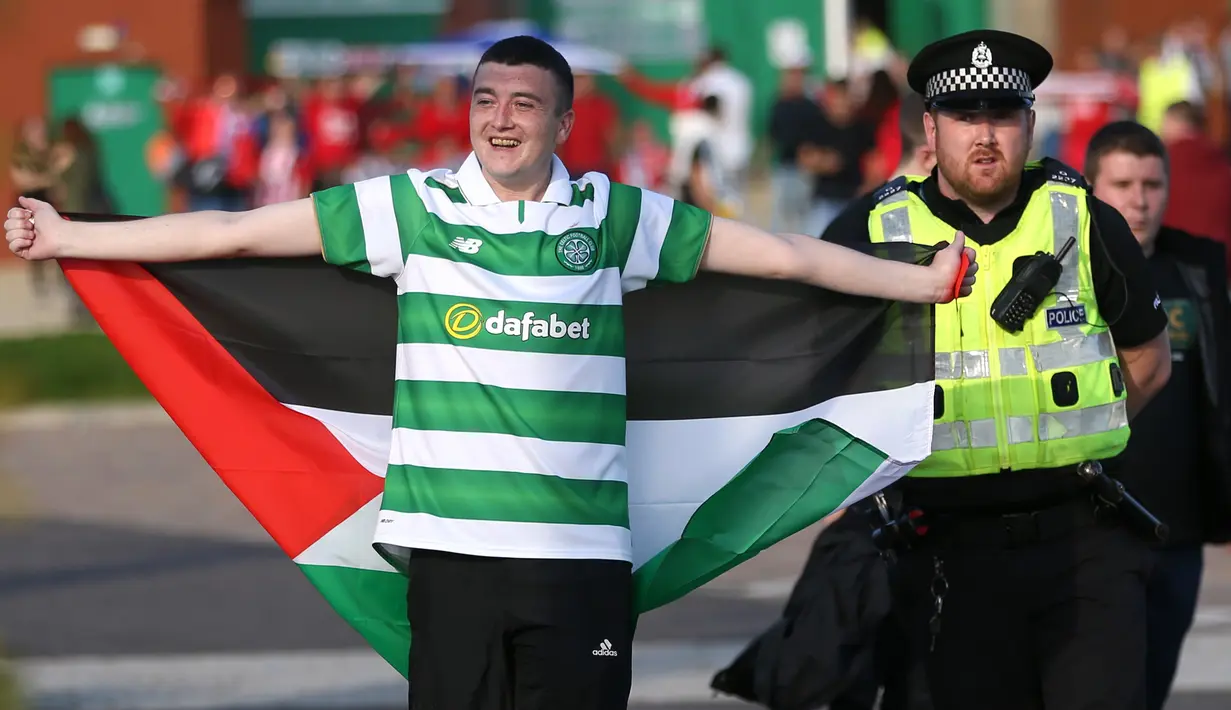 Seorang suporter membawa bendera Palestina saat akan menyaksikan pertandingan melawan Hapoel Beer Sheva di babak kualifikasi play off Liga Champions di Celtic park, (19/8). Fans Celtic telah merencanakan aksi ini sejak jauh hari. (REUTERS/Russell Cheyne)