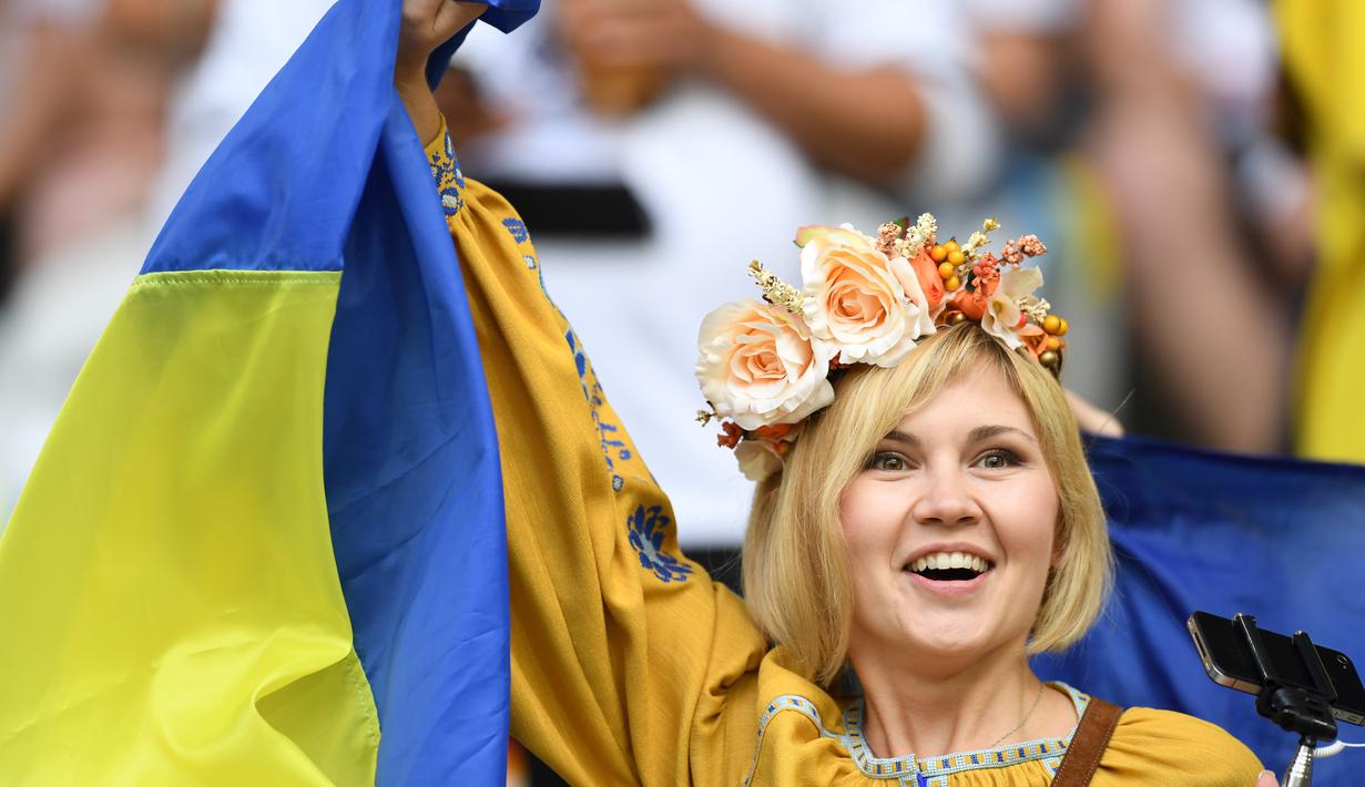 Hiasan di kepala dan bendera Ukraina menambah kecantikan suporter ini yang hadir ketika Ukraina melawan Jerman di Stade Pierre Mauroy, Lille. (12/6/2016). (AFP/Patrik Stollarz)