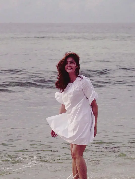 Lagi-lagi Biby asik bermain di laut. Kali ini istri Rifky Balweel memilih memakai dress putih dan membiakan rambut pirangnya terurai dan tertiup oleh hembusan angin. (Instagram/Bibyalraen13)