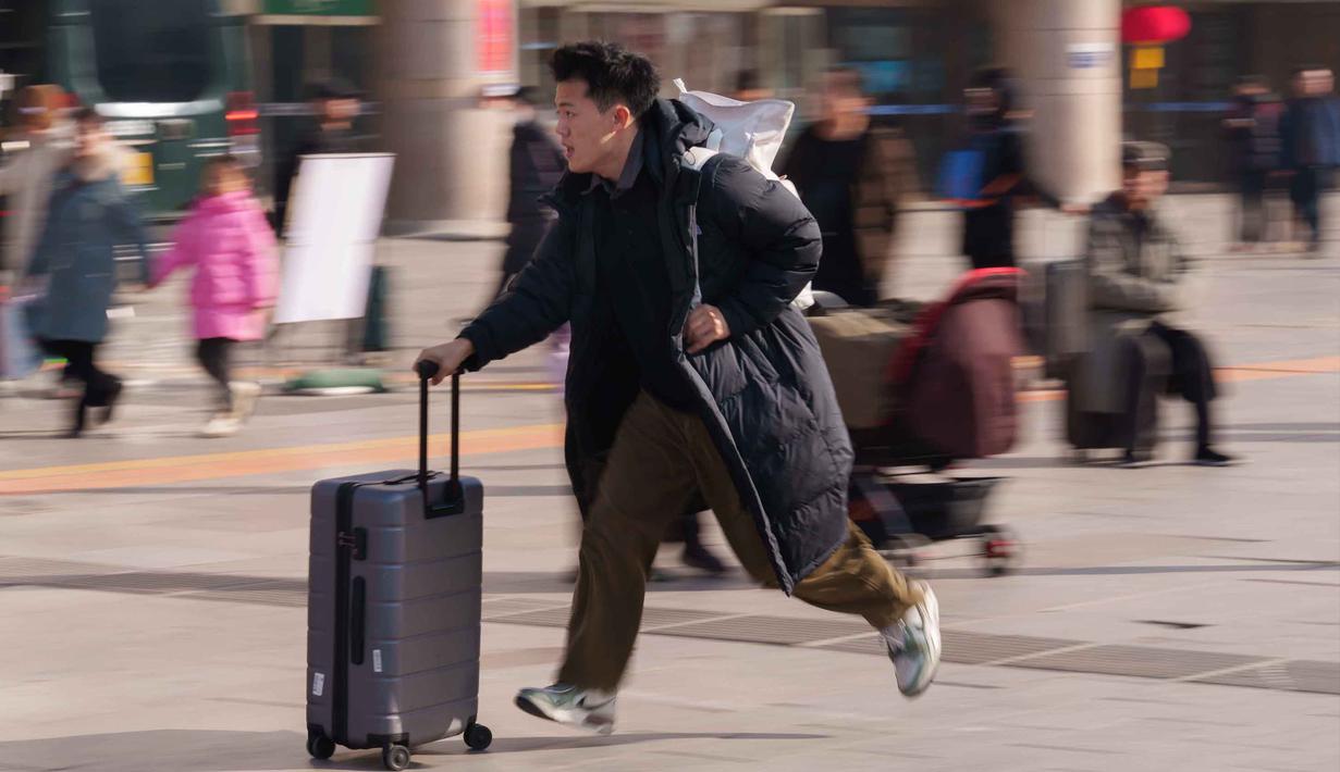 Seorang pria berlari sambil menyeret koper di stasiun kereta api saat orang-orang pulang kampung selama liburan Tahun Baru Imlek di Beijing, China, Selasa 10 Februari 2026. Gelombang migrasi penduduk tahunan terbesar China telah dimulai. (AP Photo/Vincent Thian)