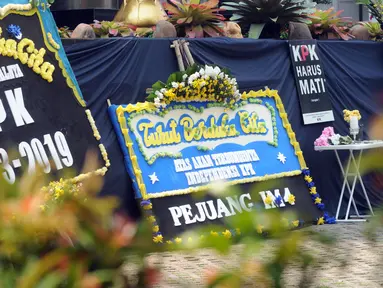 Sejumlah karangan bunga diletakkan dekat kain hitam besar yang menutupi logo KPK di Gedung Merah Putih, Jakarta, Senin (9/9/2019). Keberadaan kain hitam dan karangan bunga ini merupakan bentuk protes atas revisi Undang-undang KPK yang dinilai dapat melemahkan KPK. (merdeka.com/Dwi Narwoko)