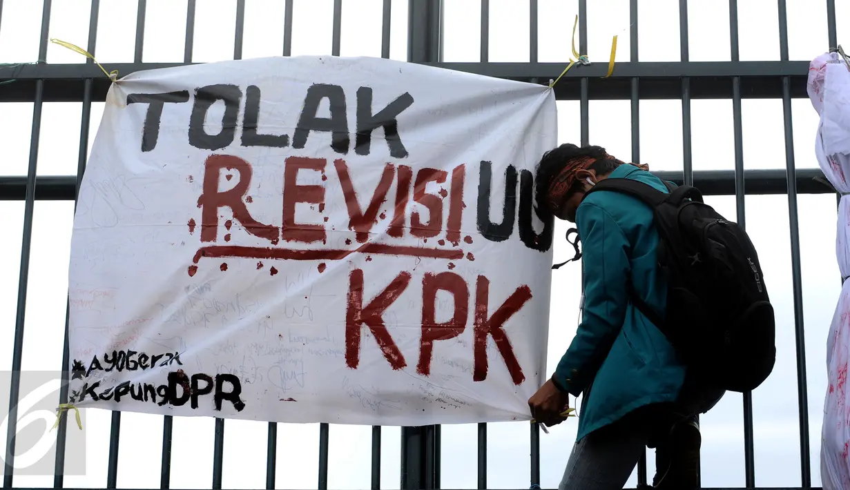 Seorang mahasiswa dari Institut Pertanian Bogor memasang tulisan penolakan saat aksi di depan Gedung Parlemen RI, Jakarta, Selasa (15/12/2015). Dalam aksinya, mereka menolak revisi UU KPK. (Liputan6.com/Helmi Fithriansyah)