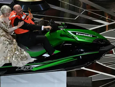 Aktris Inggris Helen Mirren duduk dibelakang Mark Bridges yang mengendarai jet ski dalam acara Academy Awards ke-90 di Hollywood, California (4/3). Mark Bridges tidak hanya memboyong piala Oscar untuk tahun ini. (AFP Photo/Mark Ralston)