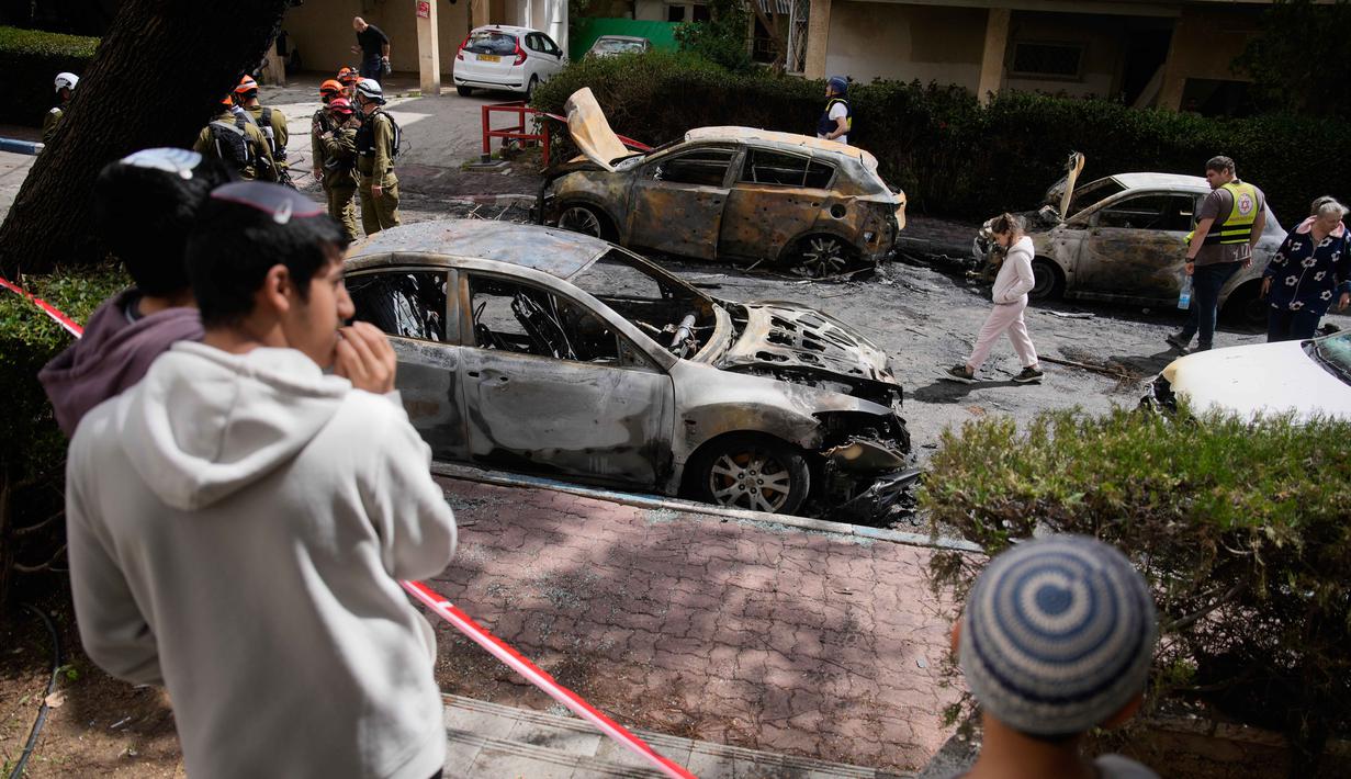 Serangan Iran tersebut menghantam area permukiman warga, menyebabkan kerusakan properti dan menghanguskan sejumlah kendaraan. Tampak dalam foto, warga dan pasukan keamanan Israel memeriksa lokasi yang terkena serangan rudal Iran di Petah Tikva, Israel, Selasa 31 Maret 2026. (AP Photo/Ohad Zwigenberg)