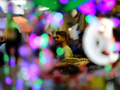 Pedagang menawarkan lentera Ramadan kepada pengunjung sebuah pasar di Kota Gaza, Kamis (25/5). Warga Palestina merayakan datangnya bulan puasa dengan memasang lentera tradisional khas Ramadan sebagai dekorasi rumah mereka. (AP Photo/Adel Hana)