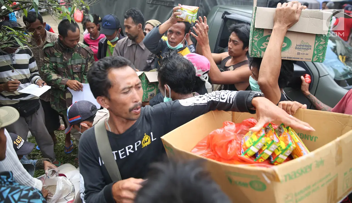 Petugas membagikan jatah mi instan ke pengungsi Gunung Agung di Posko Pengungsi Rendang, Bali, Sabtu (2/12). Keterbatasan bahan makanan membuat warga antusias setiap kali pembagian makanan. (Liputan6.com/Immanuel Antonius)