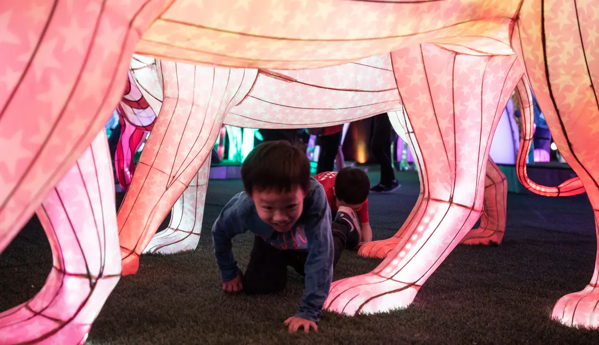 Dua bocah bermain di dekat seni instalasi cahaya yang berjudul "Halo Park" di Chaoyang Park, Beijing (7/5). Dalam pameran ini lebih dari 20 hiburan visual acousto-optik ditampilkan. (AFP/Fred Dufour)