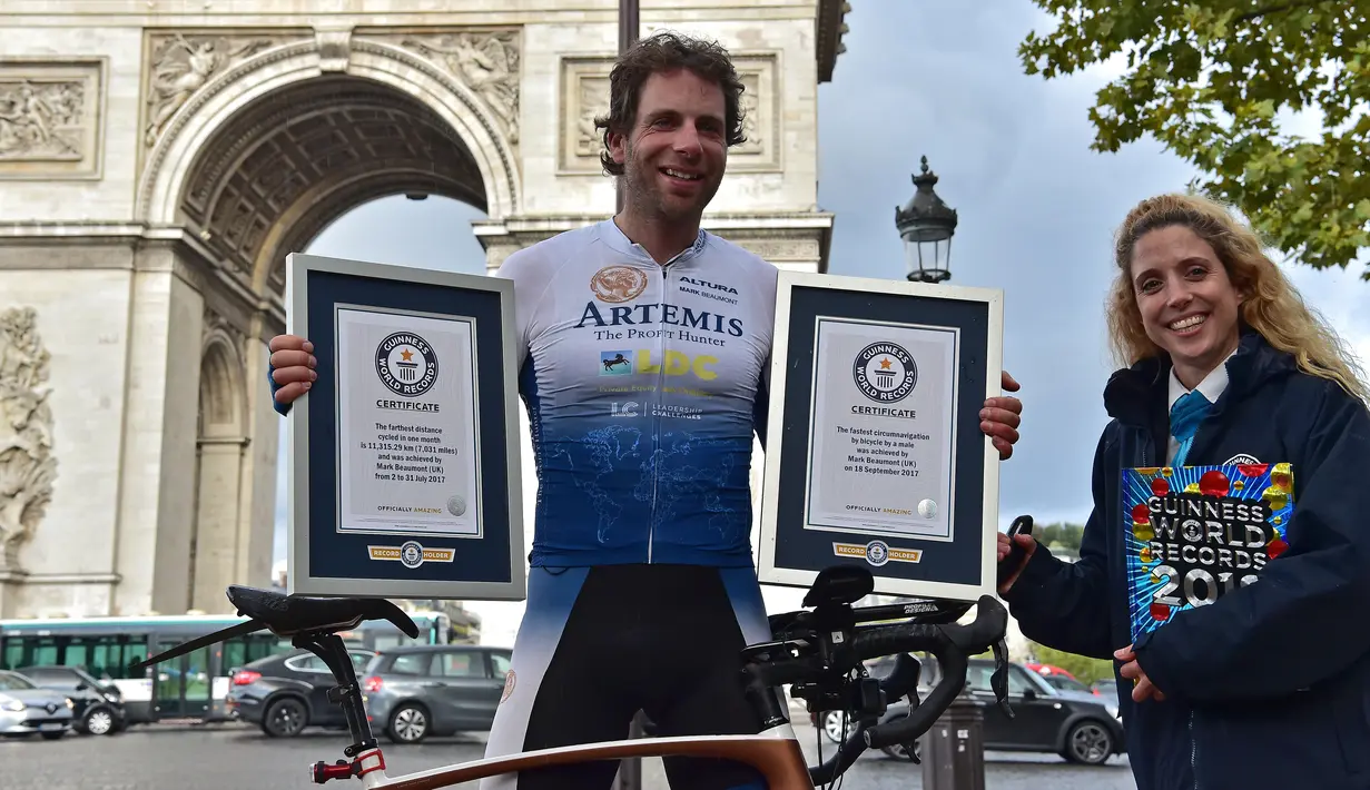 Pembalap sepeda Inggris, Mark Beaumont (34) berpose dengan sertifikat Guinness World Records setibanya di Arc de Triomphe, Paris, setelah menyelesaikan tur keliling dunia dalam waktu 78 hari, Senin (18/9). (CHRISTOPHE ARCHAMBAULT / AFP)