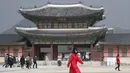 Seorang wanita mengenakan masker berjalan di Gerbang utama Istana Gyeongbok, Seoul, Korea Selatan, Sabtu (22/2/2020). Di Korea Selatan hingga kini sudah ada dua kematian akibat virus corona. (AP Photo/Lee Jin-man)