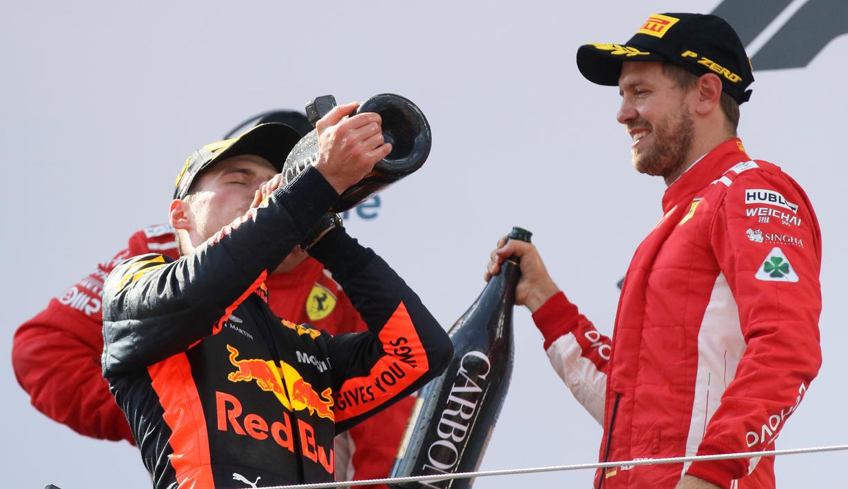 Pembalap Red Bull Max Verstappen meminum sampanye bersama dengan pembalap Ferrari, Sebastian Vettel dari Australia setelah berhasil memenangkan GP Austia di Red Bull Ring, Spielberg, Austria, (1/7). (AP Photo / Ronald Zak)