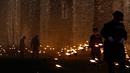 Yeoman Warders atau 'Beefeaters' menyalakan ribuan lilin di parit kering Tower of London, Inggris, Selasa (6/11). Nyala lilin membentuk instalasi yang disebut 'Beyond the Deepening Shadow: The Tower Remembers'. (AP Photo/Alastair Grant)