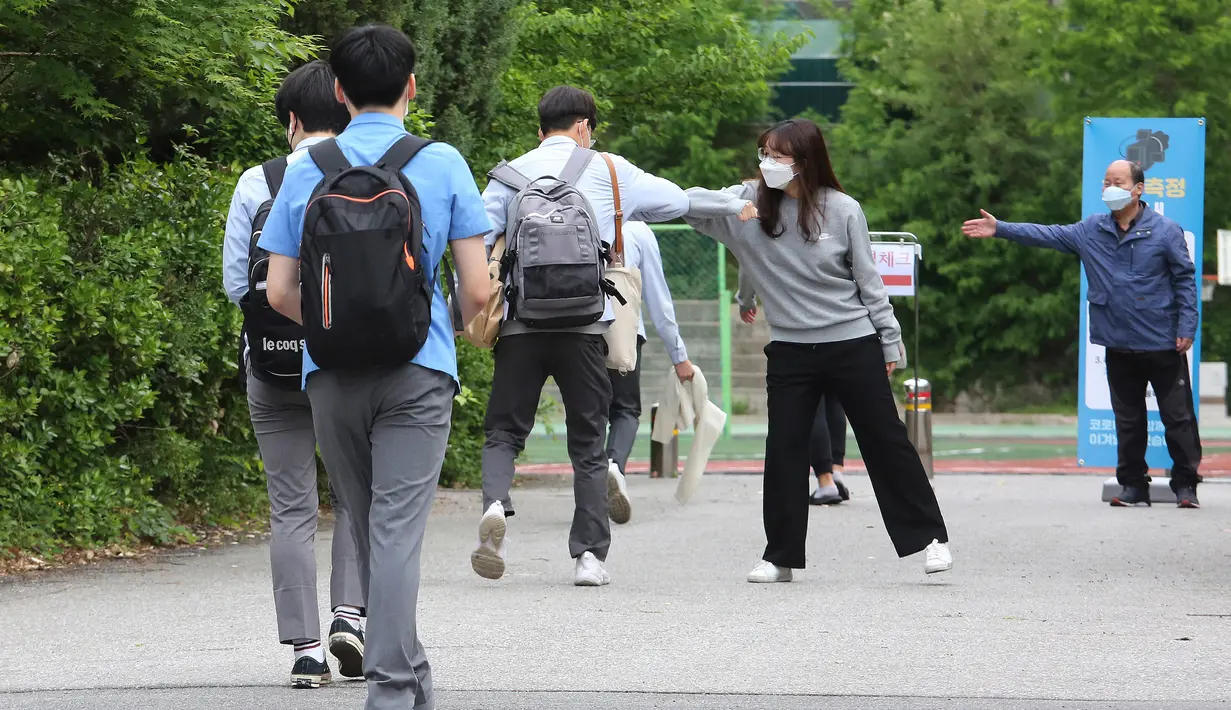 Seorang siswa senior disambut oleh seorang guru, kedua dari kanan, pada saat kedatangannya di Sekolah Tinggi Kyungbock di Seoul, Korea Selatan, Rabu, (20/5/2020). (AP Photo/Ahn Young-joon)