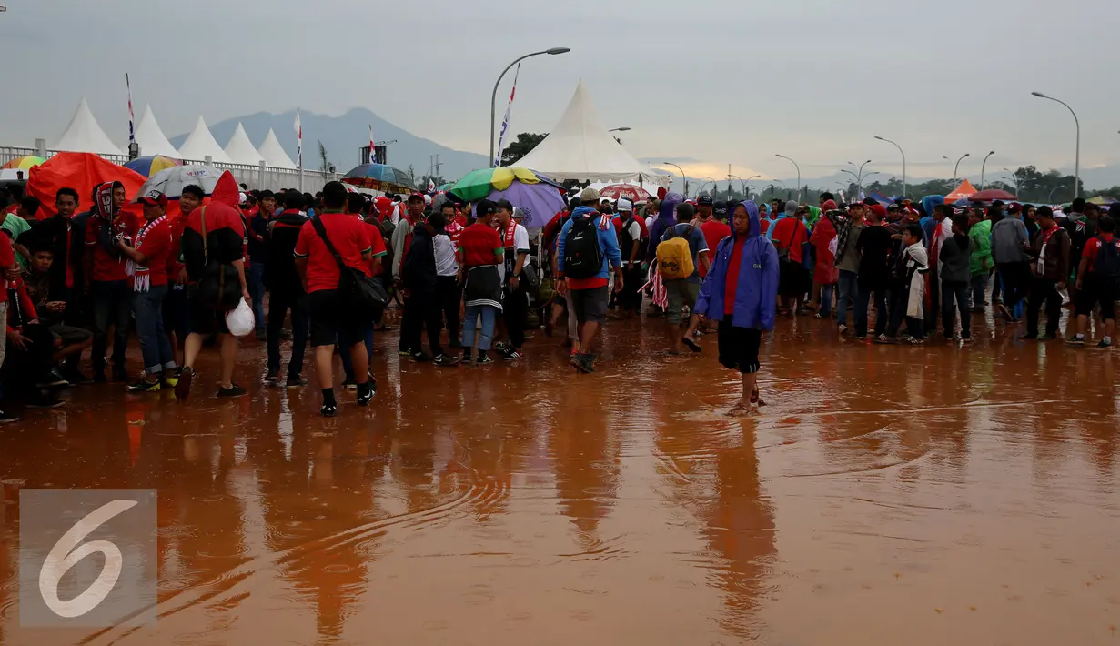 Sejumlah orang memadati sekitar Stadion Pakansari untuk menonton final leg pertama Piala AFF 2016, Bogor, Rabu (14/12). Walau di guyur hujan, pendukung tetap semangat mendukung tim sepak bola Indonesia. (Liputan6.com/Johan Tallo)