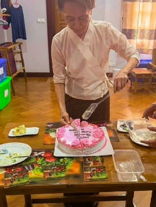 Mantan pemimpin sipil yang ditahan Aung San Suu Kyi memotong kue saat  bertemu dengan perwakilan tetap Komite Internasional Palang Merah (ICRC) untuk Myanmar Arnaude de Baecque di Naypyidaw, Myanmar, Senin, 3 Agustus 2026. (AFP/ Biro Pers dan Informasi Kepresidenan Myanmar )