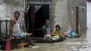 Warga duduk di luar rumah mereka di jalan banjir setelah hujan deras, di Karachi, Pakistan, Selasa (30/7/2019). Hujan deras yang melanda kota Karachi, pelabuhan selatan Pakistan, memicu banjir dan menewaskan enam orang. Pihak berwenang menutup sekolah. (AP/Photo/Fareed Khan)